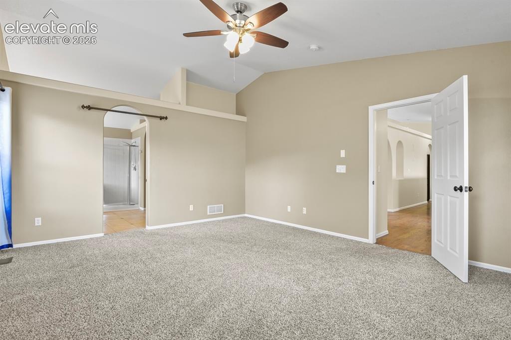 Image 23 of 48: Spacious room featuring vaulted ceilings, Ceiling Fan and neutral-toned wal