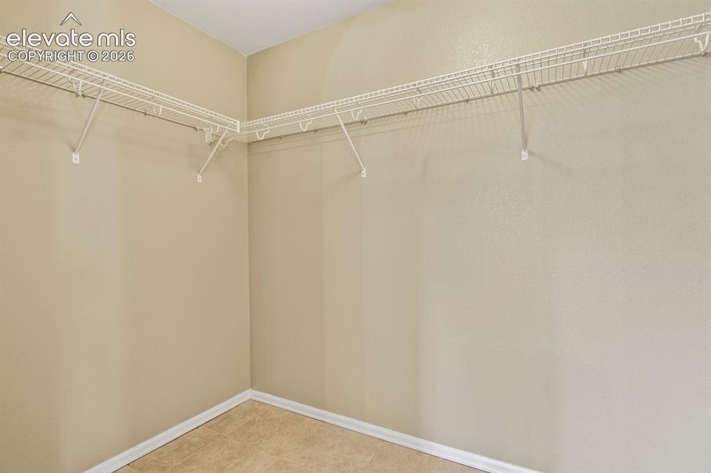 Image 25 of 48: Master Bedroom Walk in closet with wire shelving system and neutral wall pa