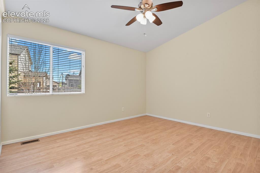 Image 29 of 48: Spacious room featuring vaulted ceilings, a ceiling fan with integrated lig