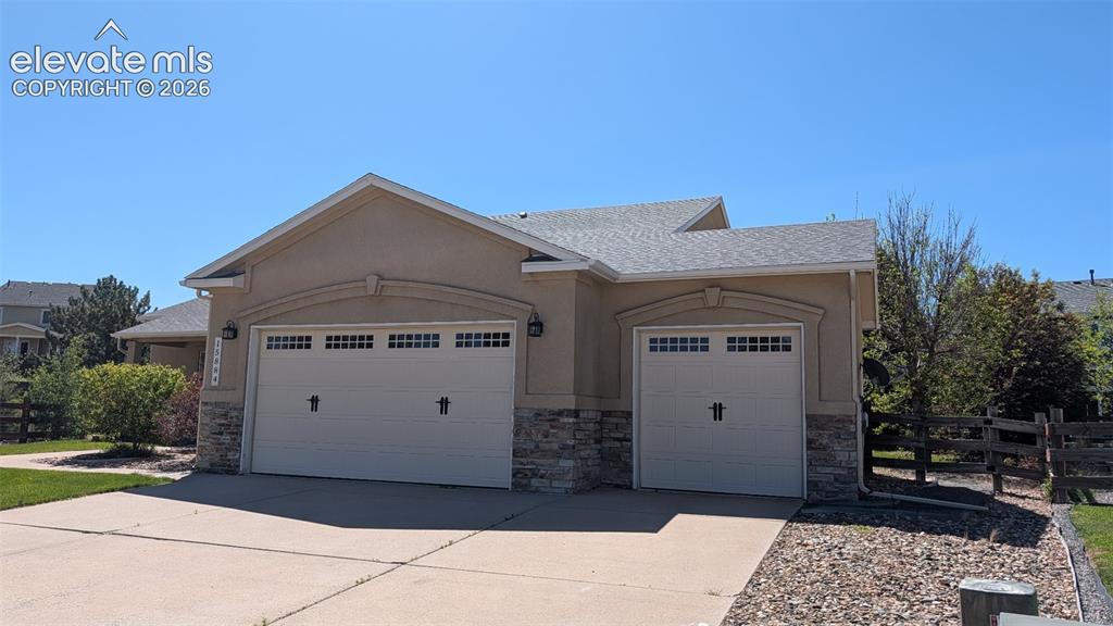 Image 3 of 48: Stucco exterior featuring a two-car garage with decorative windows and scon