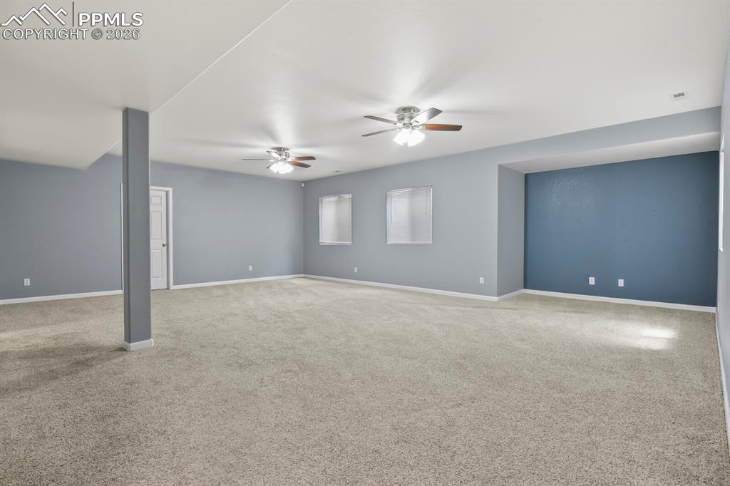 Image 32 of 43: Spacious room featuring neutral carpeting, light blue wall paint, and multi