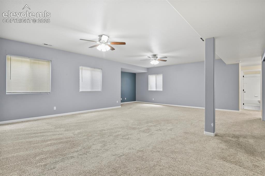 Image 32 of 48: Spacious room with light gray walls, plush carpeting, multiple ceiling fans