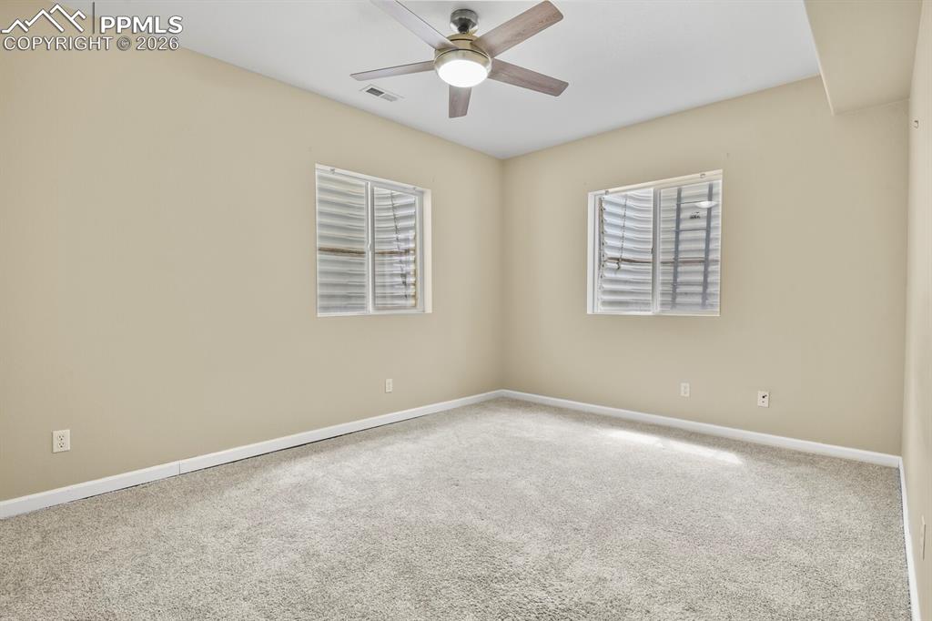 Image 33 of 43: Spacious room featuring neutral carpeting, light-toned wall paint, two wind