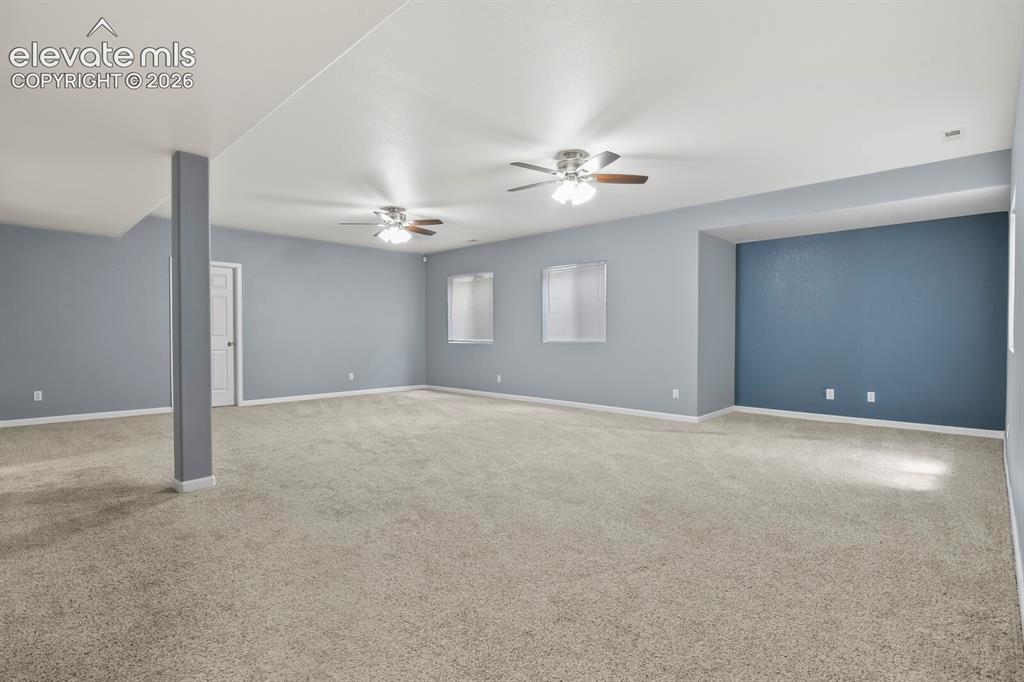 Image 36 of 48: Spacious room featuring neutral carpeting, light blue wall paint, and multi