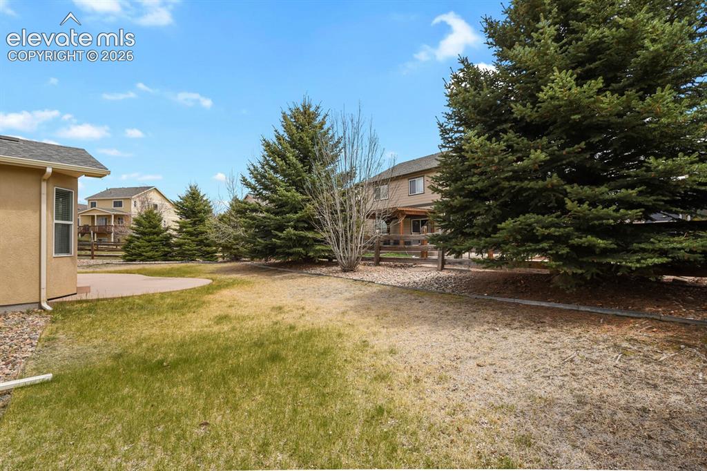Image 45 of 48: Expansive backyard featuring a curved paver patio, a partial grass lawn, an