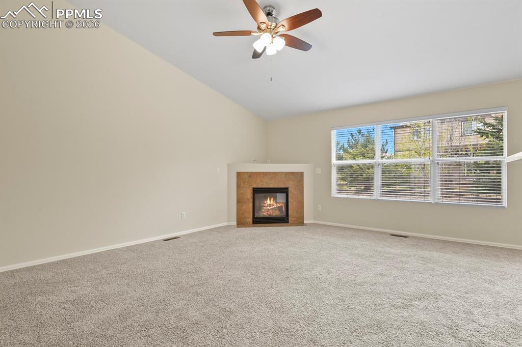Image 7 of 43: Spacious living area featuring a vaulted ceiling with a ceiling fan, a gas 