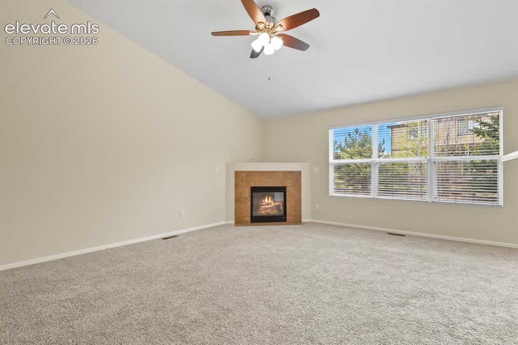 Image 8 of 48: Spacious living area featuring a vaulted ceiling with a ceiling fan, a gas
