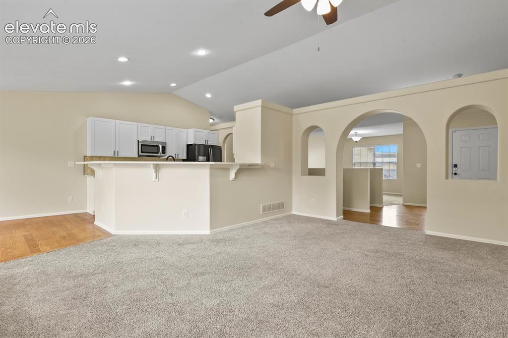 Image 9 of 48: Spacious living area featuring vaulted ceilings, recessed lighting, and a n