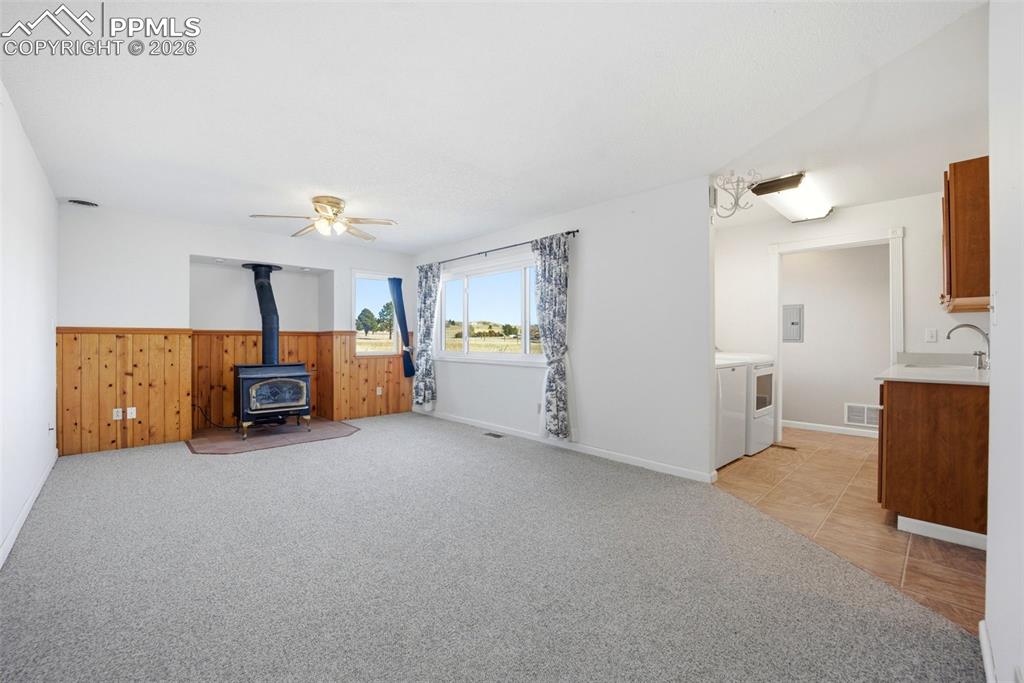 Image 18 of 50: Family room with wood stove and wainscoting