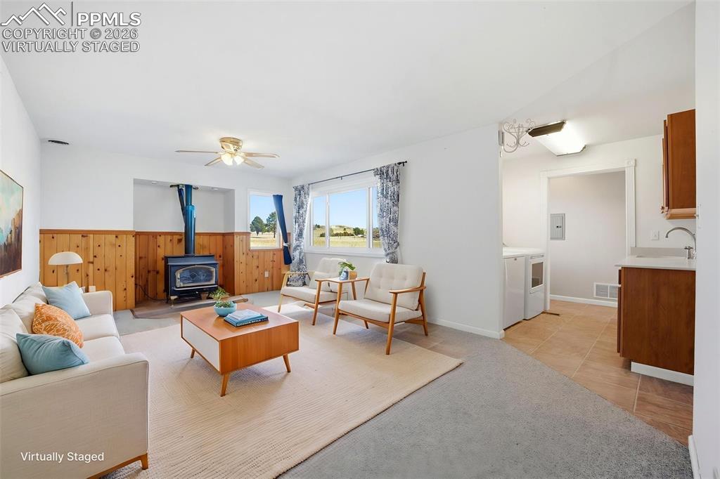 Image 19 of 50: Virtually staged family room featuring a wood stove, light carpet, light ti