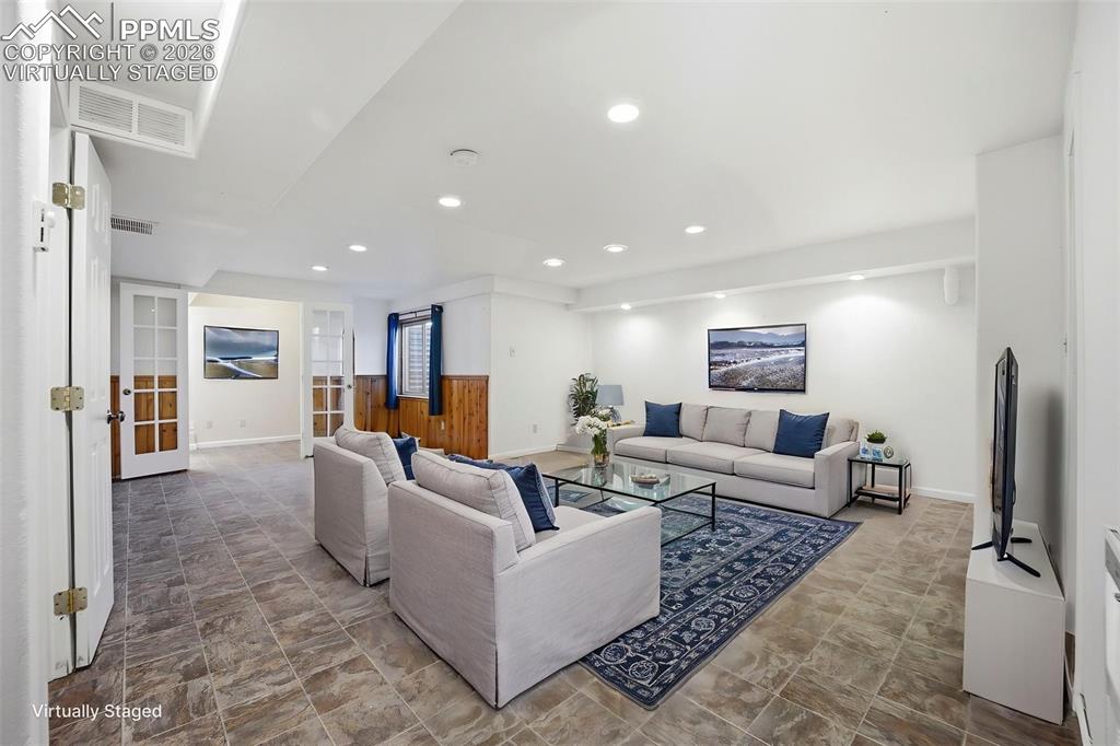 Image 34 of 50: Virtually staged large basement area with small office area with french doo