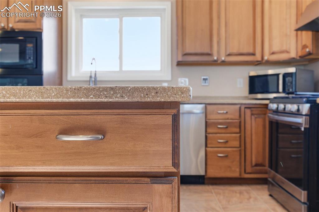 Image 5 of 50: Kitchen with wood finish cabinets, Corian countertops, and light tile patte