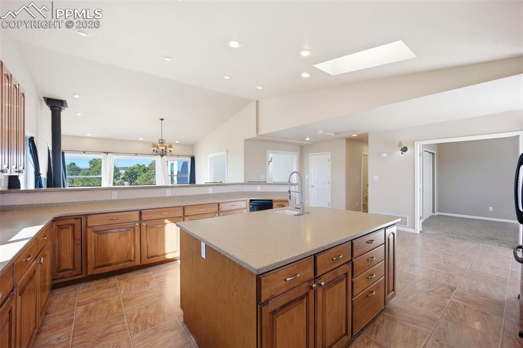 Image 7 of 50: Kitchen featuring wood finish cabinetry, lofted ceiling, a center island wi