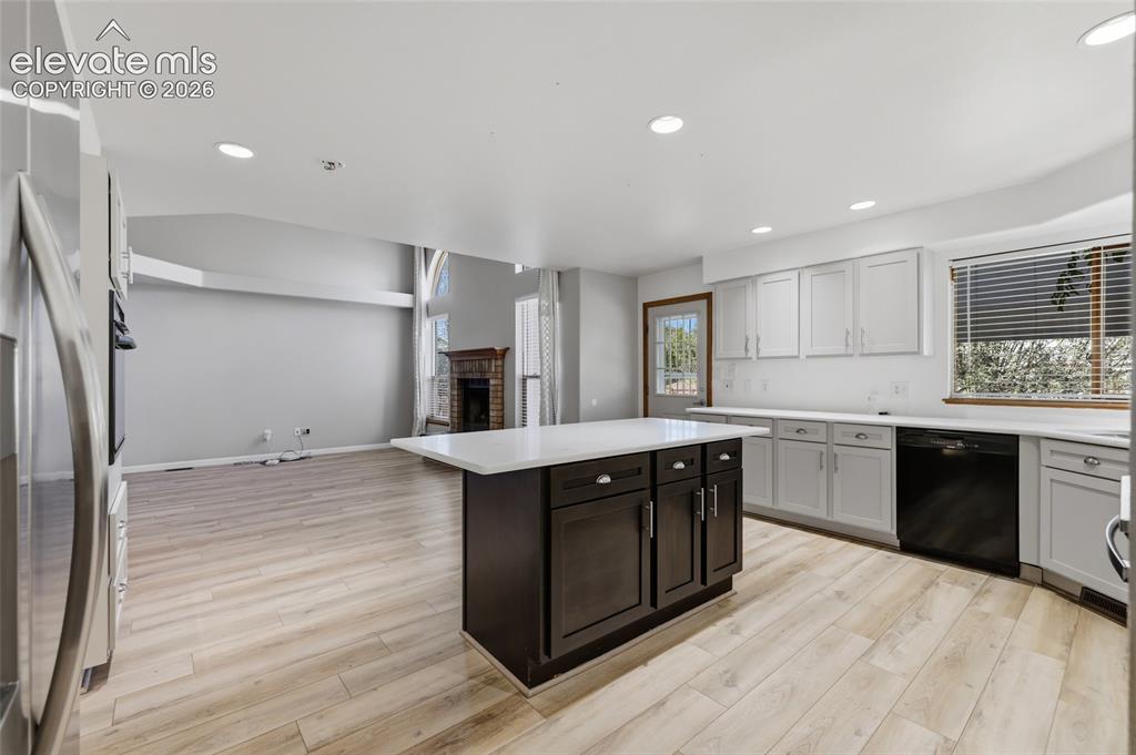 Image 11 of 50: Kitchen featuring light wood-finish flooring, a dark wood-finish island wit
