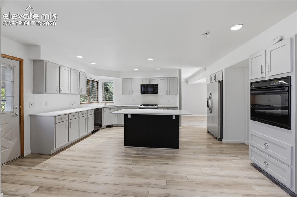 Image 12 of 50: Expansive kitchen featuring wood-finish flooring, light grey cabinetry, a c