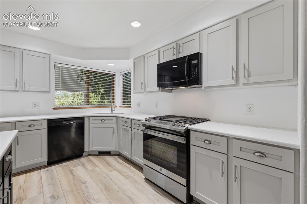 Image 13 of 50: Kitchen featuring light wood-finish flooring, light gray cabinetry, white c