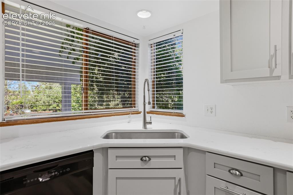 Image 14 of 50: Stainless steel sink with a gooseneck faucet, light-toned countertops, and 