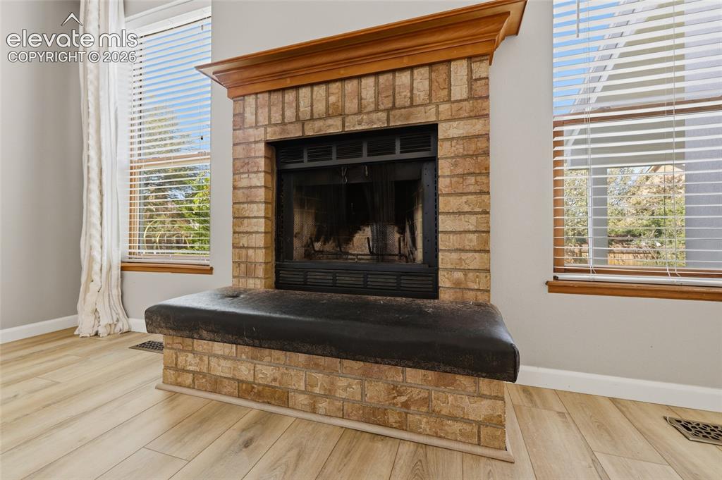 Image 16 of 50: Brick fireplace with a wood mantel and a built-in hearth seat, paired with
