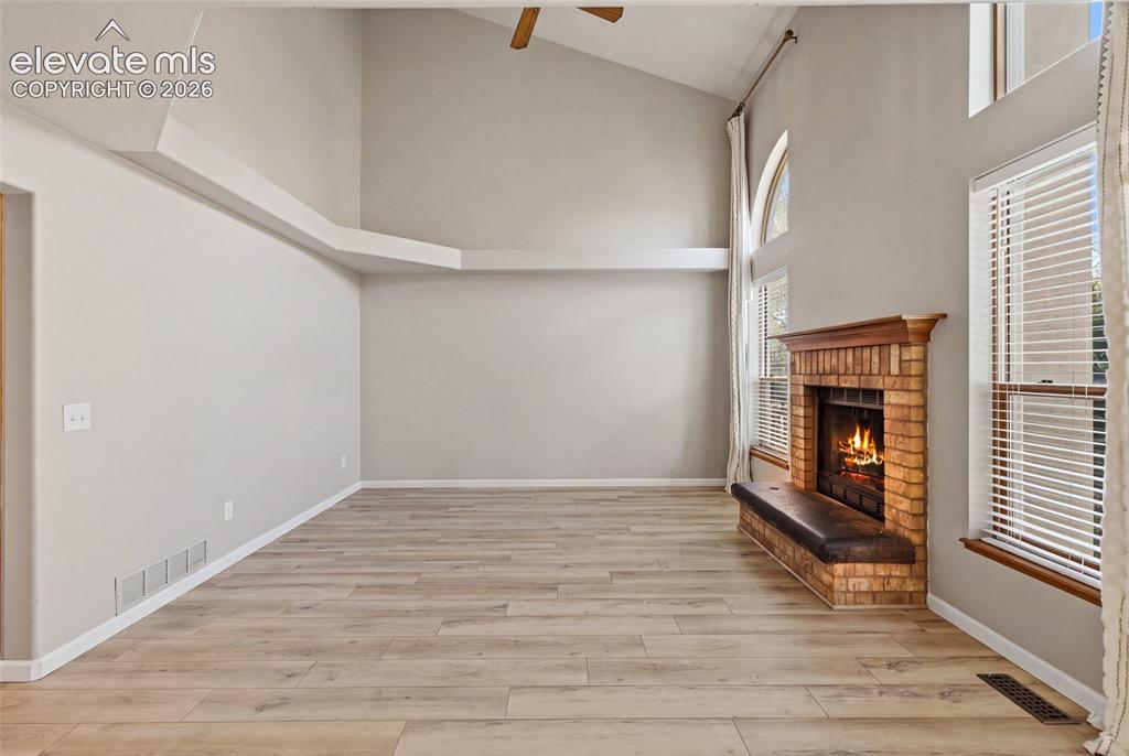 Image 18 of 50: Vaulted ceiling, wood-finish flooring, brick fireplace with wood mantel, mu