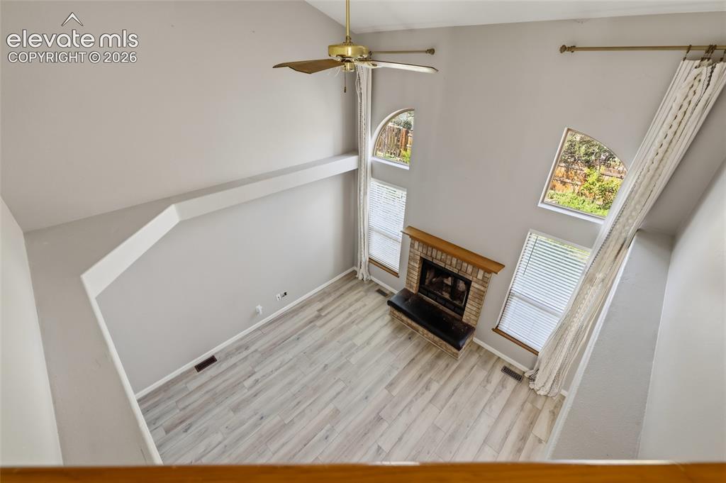 Image 23 of 50: Two story vaulted ceilings, light wood-finish flooring, a brick-surround fi