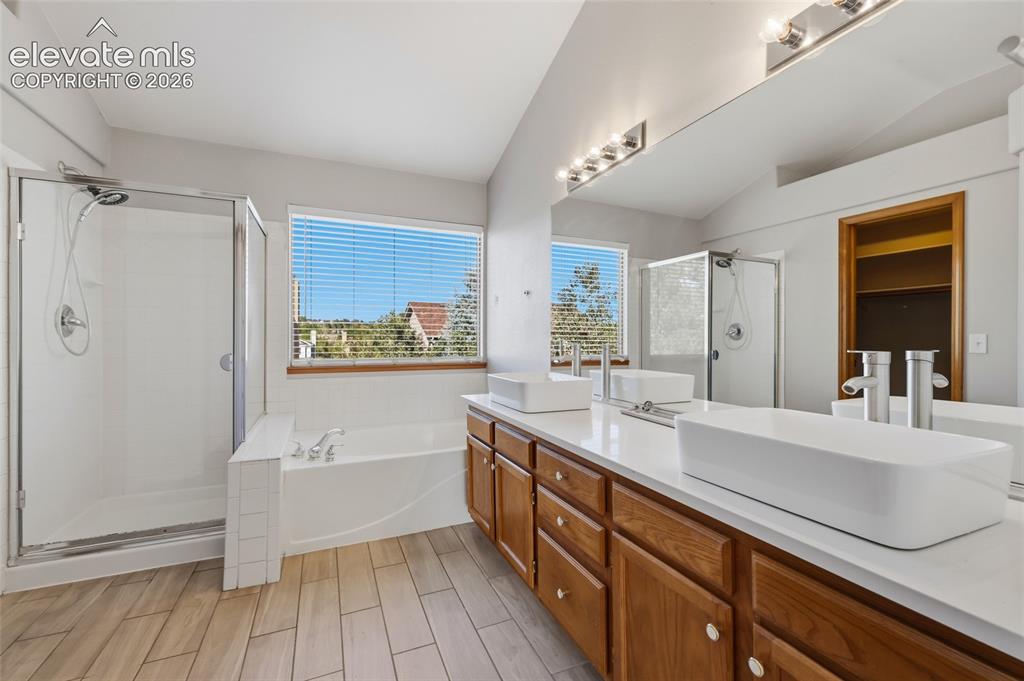 Image 27 of 50: Dual vessel sinks, wood-finish vanity, quartz countertop, walk-in shower wi