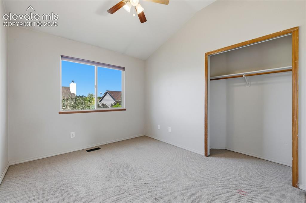 Image 29 of 50: Vaulted ceiling with a ceiling fan, dual-pane window, wall-to-wall carpetin