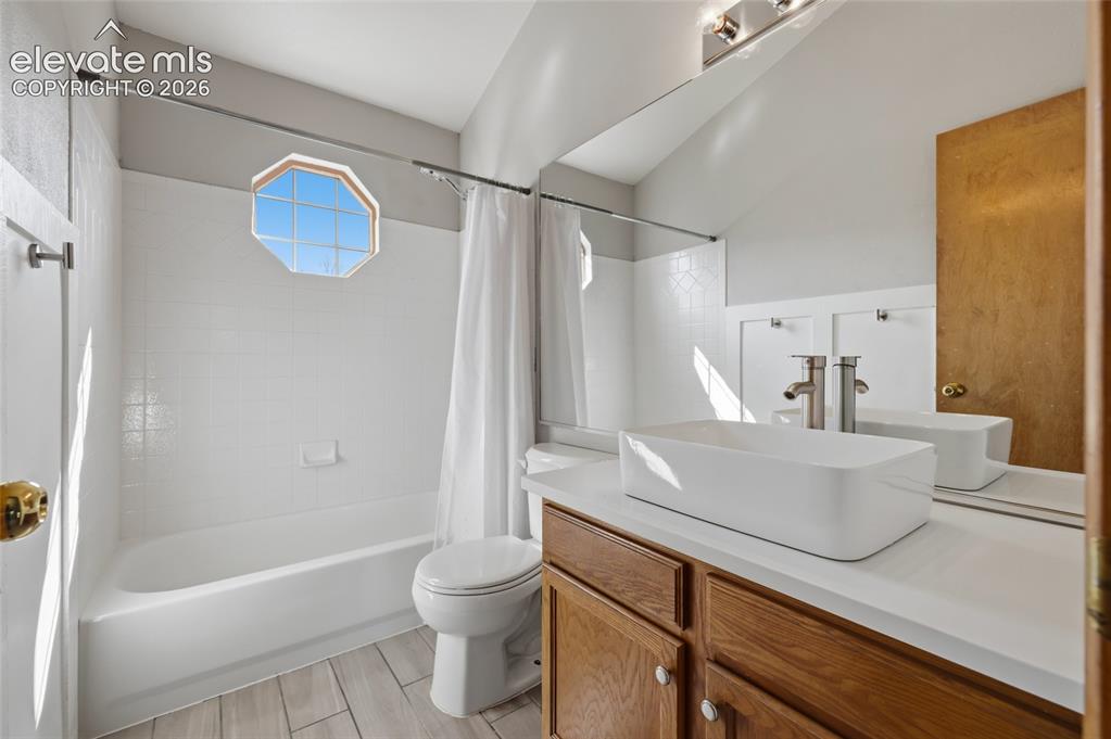 Image 32 of 50: upper full bathroom featuring a white bathtub, octagonal window, white tile