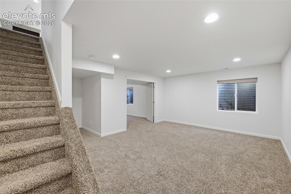 Image 33 of 50: Carpeted staircase leading to a spacious room with recessed lighting, an eg
