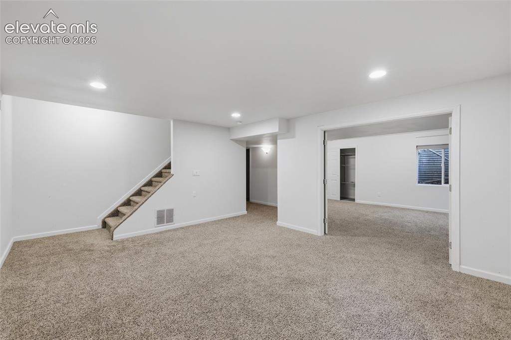 Image 34 of 50: Spacious interior with neutral carpeting, recessed lighting, and a carpeted