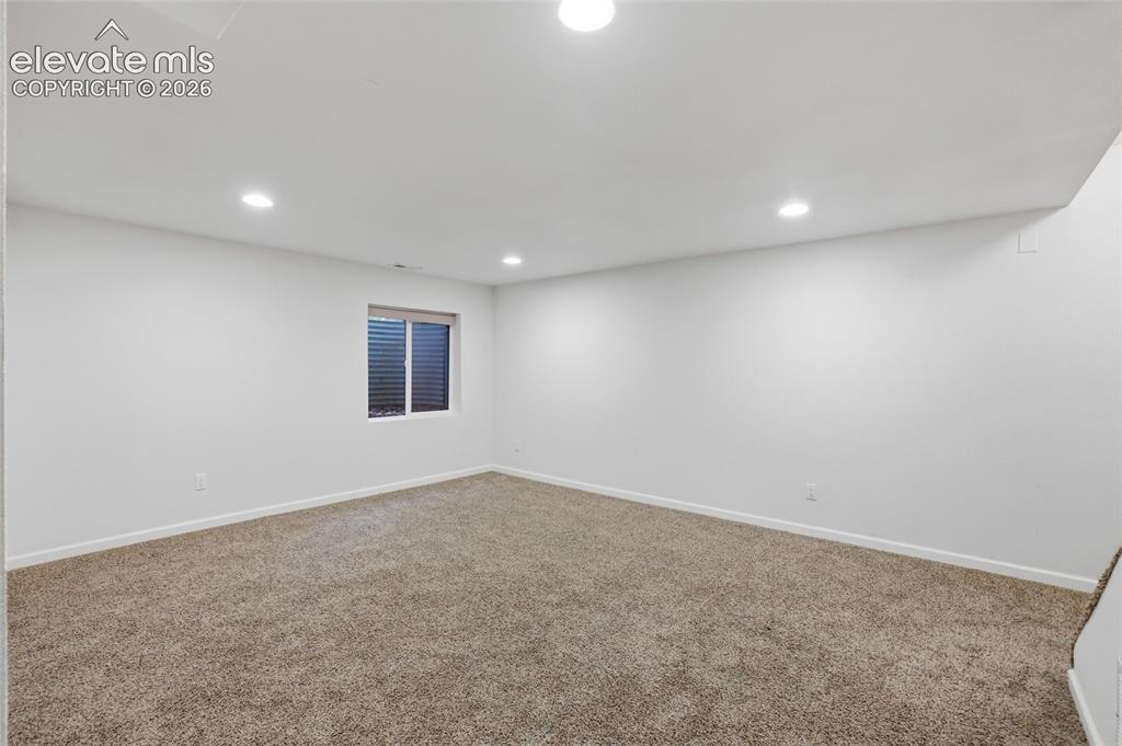 Image 36 of 50: Recessed lighting, neutral wall paint, and textured carpeting