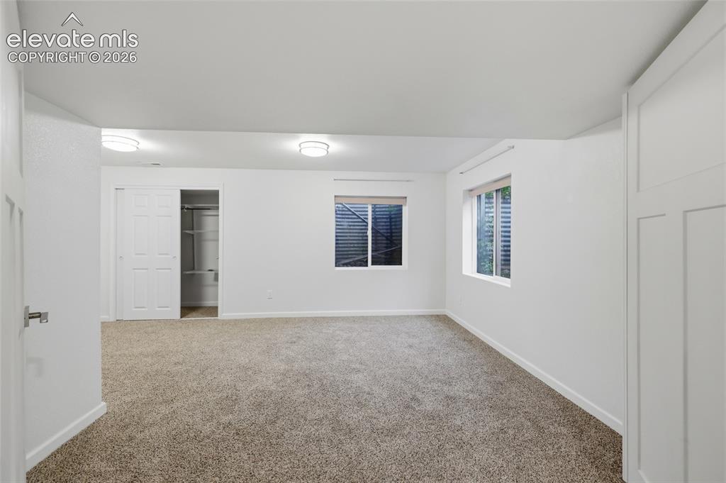 Image 38 of 50: Plush carpeting with white walls, two windows, two overhead light fixtures,