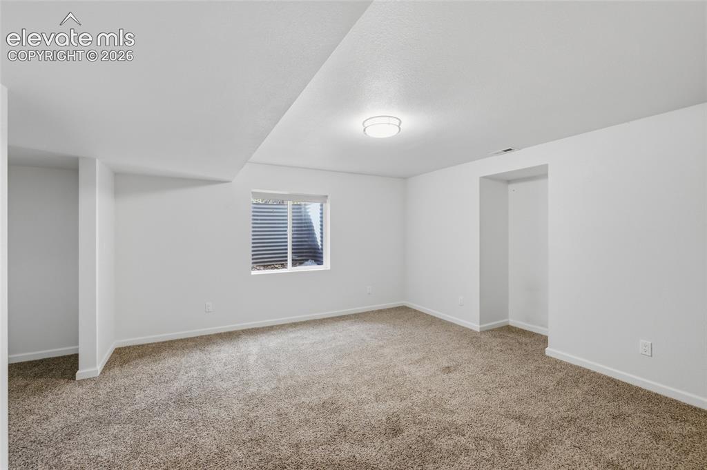 Image 41 of 50: Expansive carpeting, recessed window with horizontal blinds, and a built-in