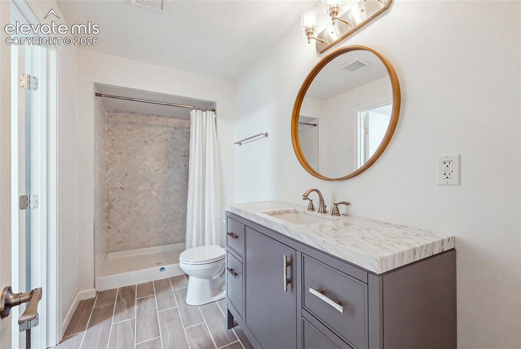 Image 42 of 50: Basement Bathroom featuring a dark gray vanity with a light-toned counterto
