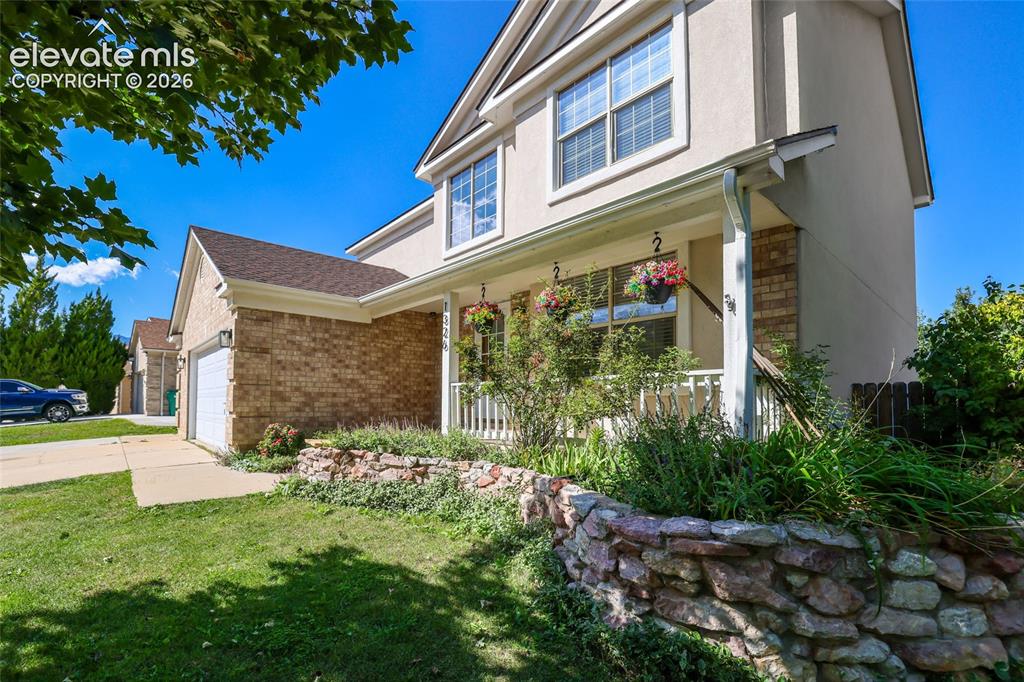 Image 49 of 50: Two-story residence featuring a brick and stucco exterior, an attached gara