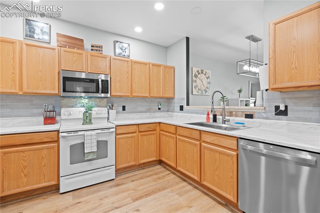 Image 10 of 29: Kitchen with stainless steel appliances, light countertops, backsplash, lig