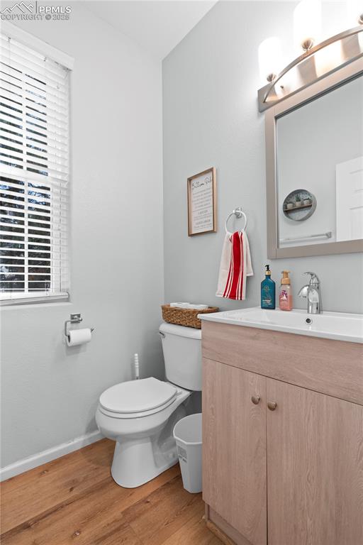 Image 13 of 29: Half bathroom with wood finished floors, vanity, and plenty of natural ligh