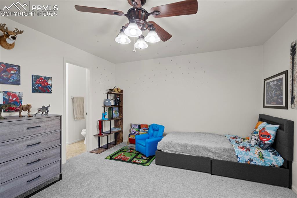 Image 18 of 29: Bedroom with light carpet, ensuite bathroom, and a ceiling fan