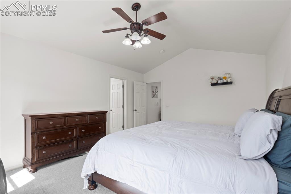 Image 23 of 29: Bedroom with vaulted ceiling, light carpet, and ceiling fan