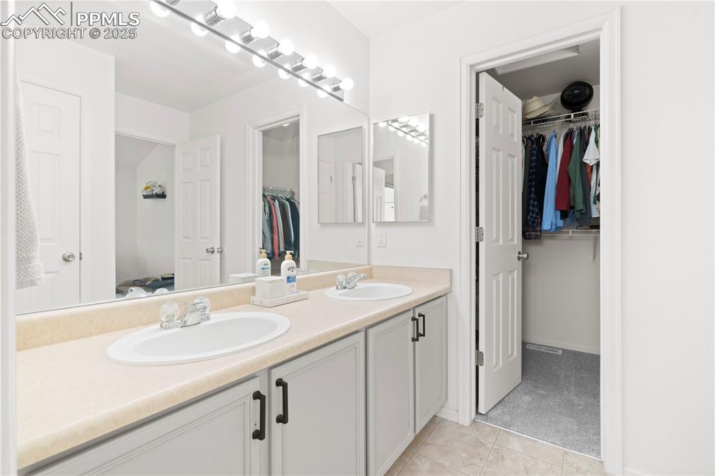 Image 25 of 29: Bathroom with double vanity, tile patterned flooring, and a spacious closet