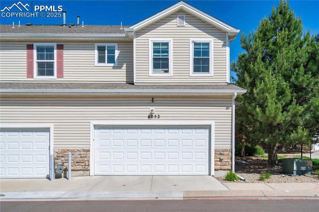 Image 3 of 29: View of front of home with stone siding, an attached garage, and concrete d