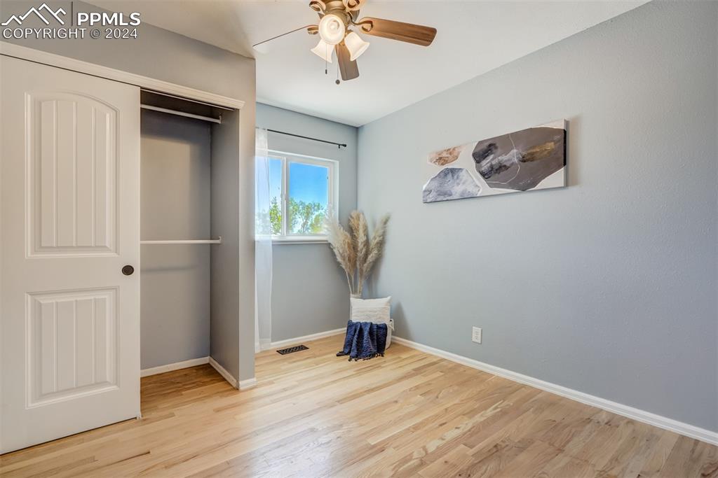 Image 24 of 33: Bedroom featuring light hardwood / wood-style floors, ceiling fan, and a cl