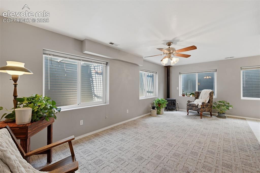 Image 19 of 31: Another view of the basement with wood burning stove and fan!