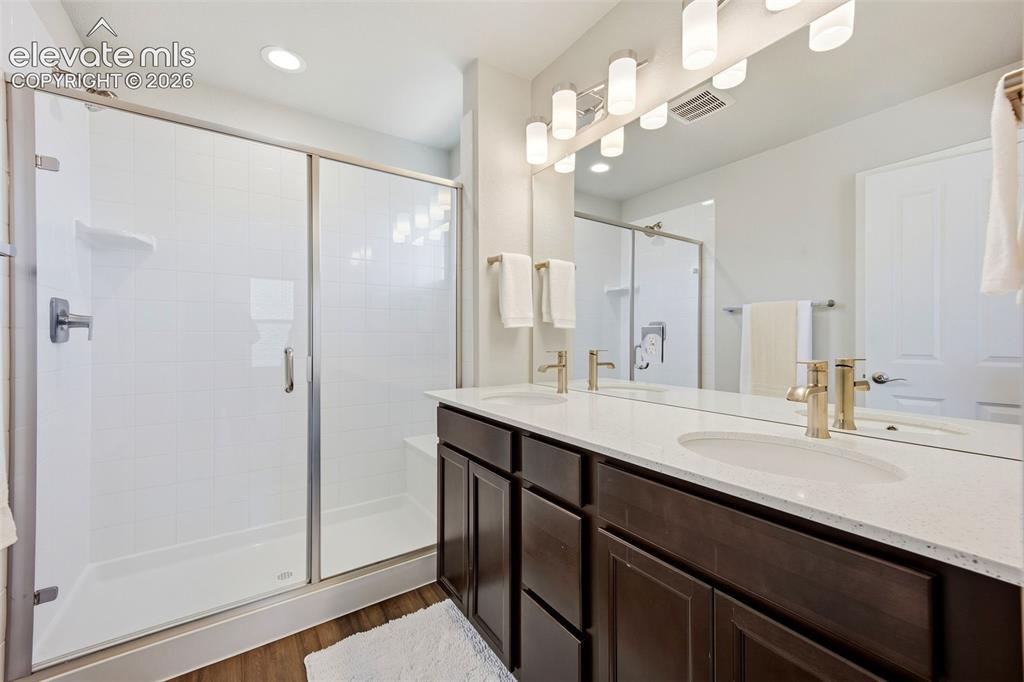 Image 31 of 49: Primary bath with walk in spa shower and double vanity
