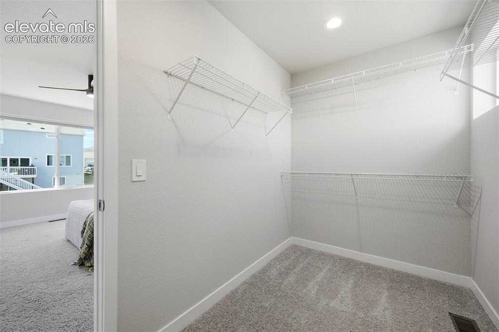 Image 32 of 49: Primary walk in closet with window and built in shelving