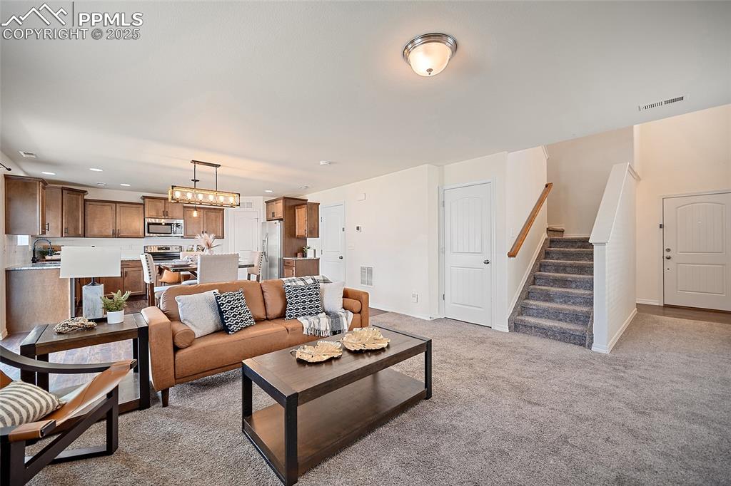Image 12 of 50: Living area featuring light carpet, stairs, and recessed lighting