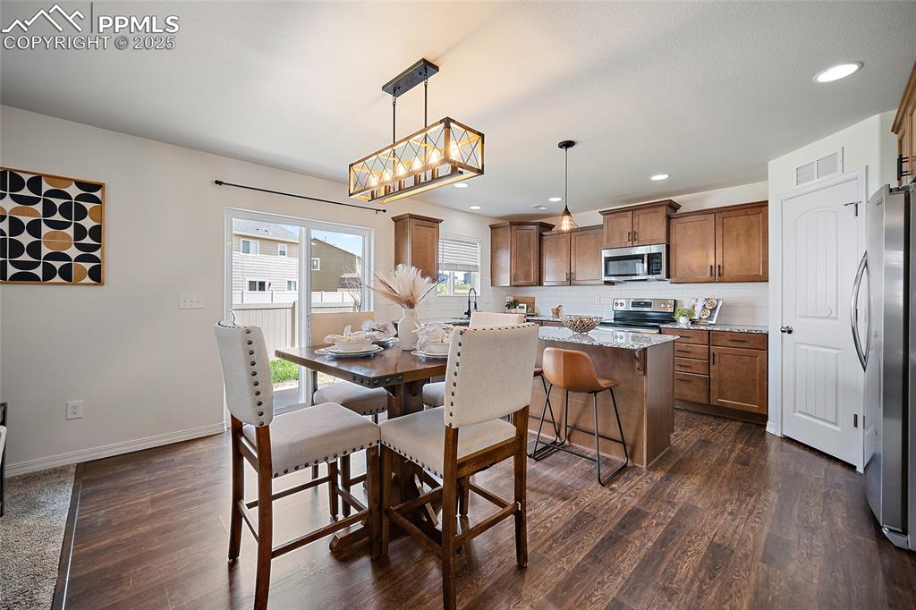 Image 15 of 50: Dining area with dark wood-type flooring and recessed lighting