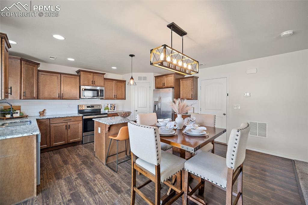Image 16 of 50: Dining room with dark wood-style flooring, recessed lighting, and a chandel