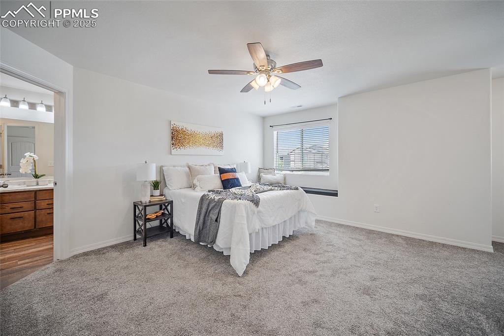 Image 29 of 50: Bedroom featuring light colored carpet, ensuite bathroom, and a ceiling fan