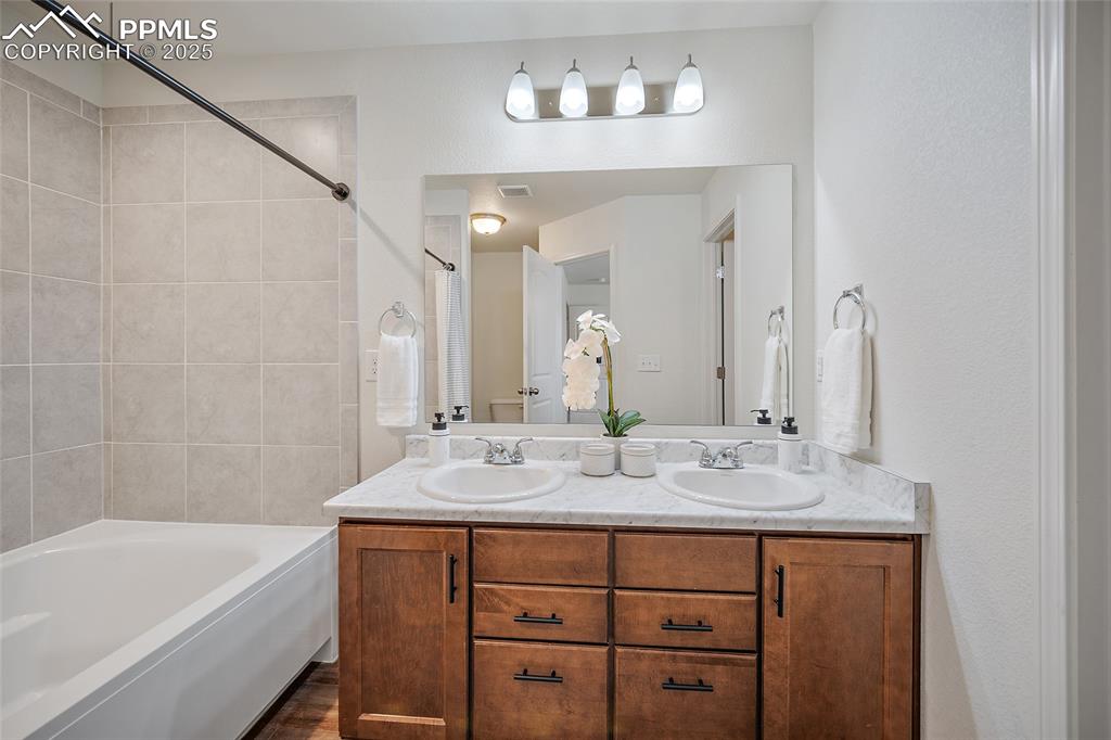 Image 3 of 50: Bathroom with double vanity and shower / bathtub combination