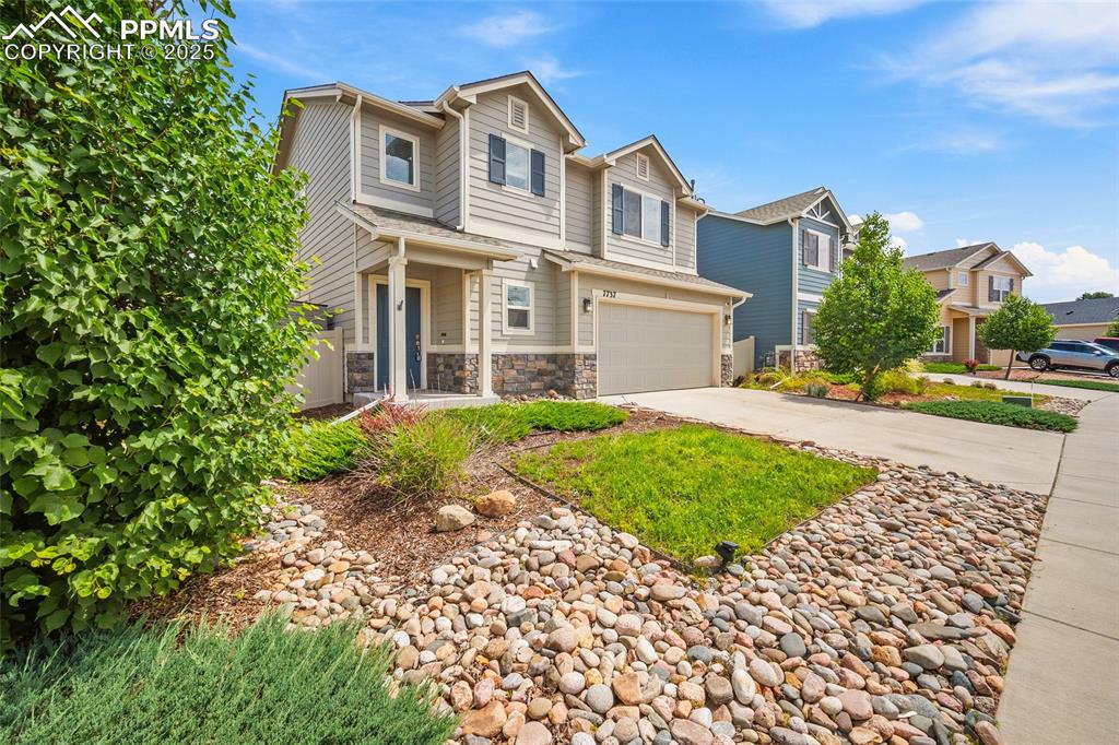 Image 32 of 50: View of front of home featuring concrete driveway, a garage, and stone sidi
